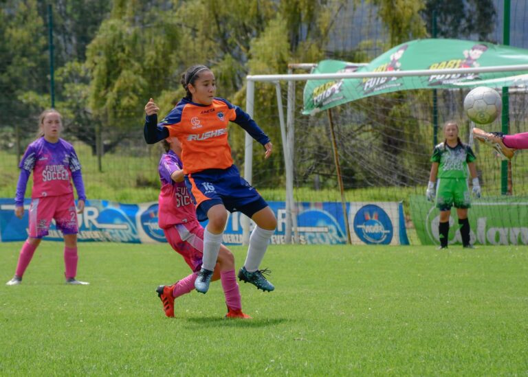 Young female soccer players in action during a sunny outdoor match.
