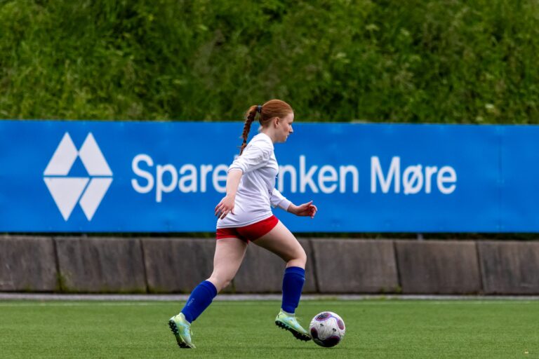 Dynamic shot of a female football player dribbling at a field in Norway.