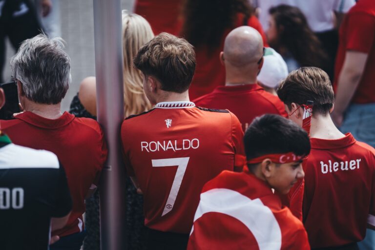 Football enthusiasts gather in team jerseys, celebrating their passion for the game outdoors.