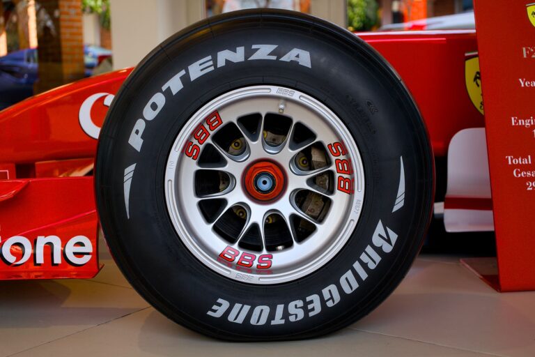 Detailed close-up of a Bridgestone Ferrari race car wheel in an indoor showroom setting.