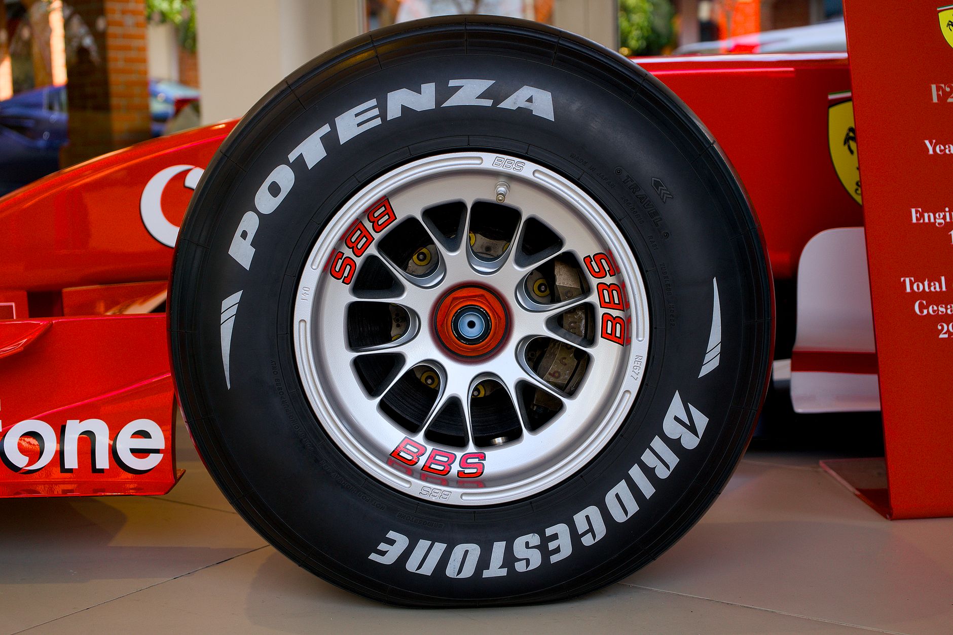Detailed close-up of a Bridgestone Ferrari race car wheel in an indoor showroom setting.