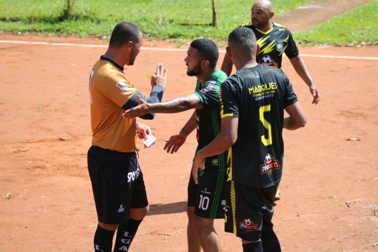 A heated moment on the field as a referee shows a card to a player during a sunny soccer match.