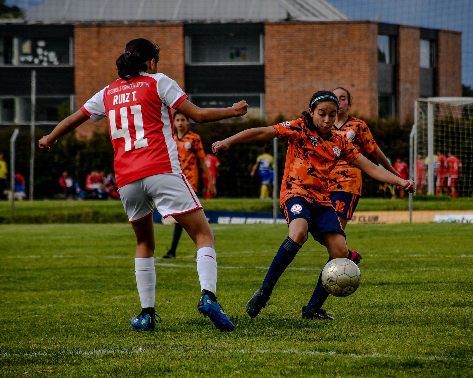 A dynamic soccer match between girls' teams in colorful sportswear on a grassy field.