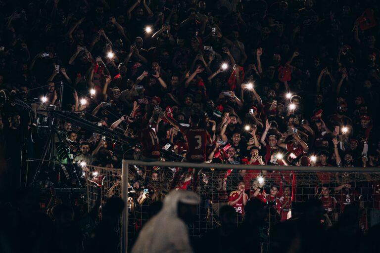 Fans cheering during a thrilling football match under night lights, capturing the vibrant atmosphere.
