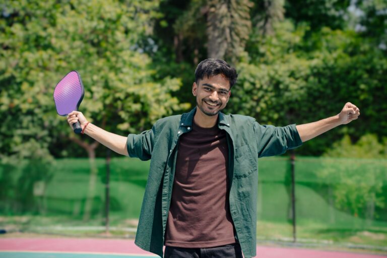 Energetic young man celebrating victory in an outdoor pickleball game on a sunny day.