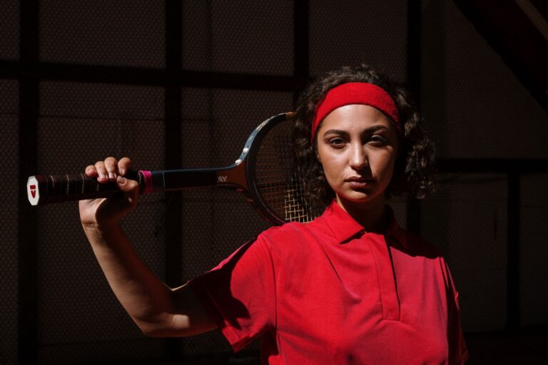Portrait of a serious female tennis player holding a racket indoors.