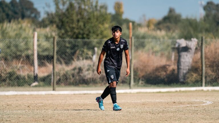 A young soccer player in black uniform focused during a game on an outdoor field.