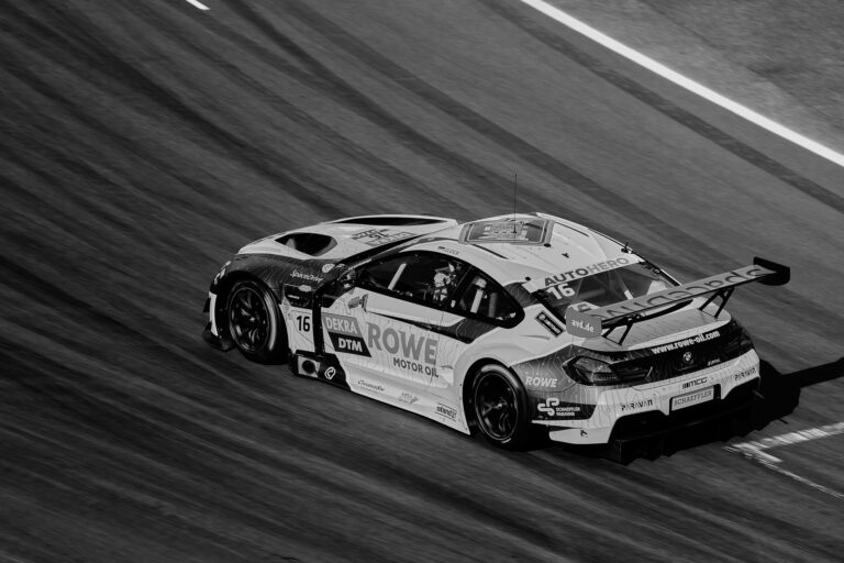 A dynamic black and white photo of a high-speed race car on a track, capturing motion and speed.