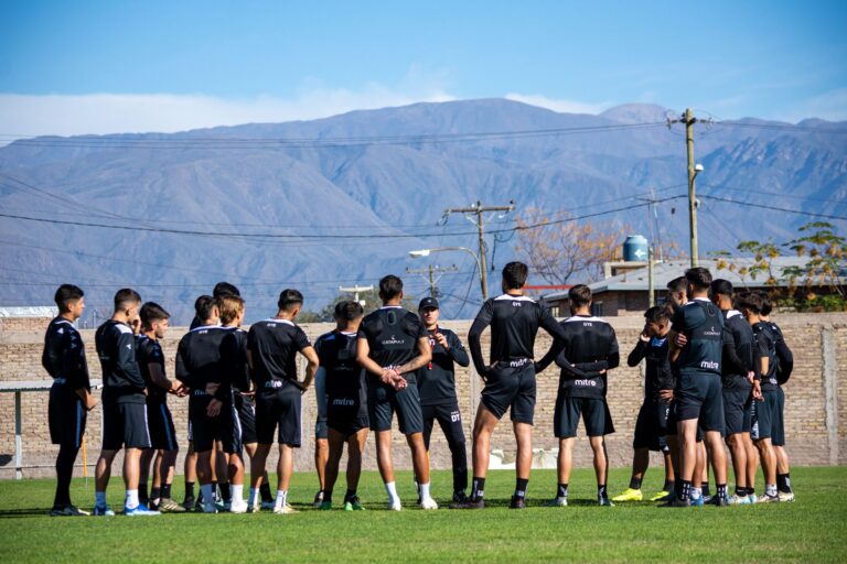 A group of footballers training outdoors with mountains in the background.