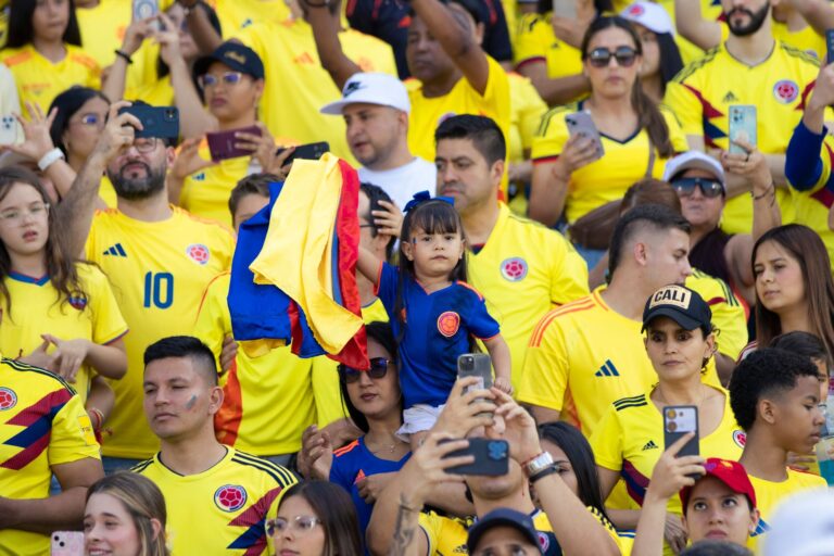 Excited Colombian fans gather with national flags at a football match, showcasing team spirit.