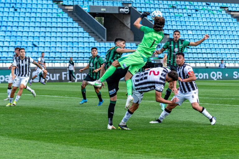 Dynamic scene of a goalkeeper leaping for the ball in a soccer match, showcasing team sports energy.