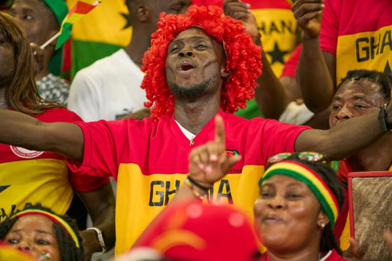 Fans passionately supporting Ghana at an intense soccer match in the stadium.