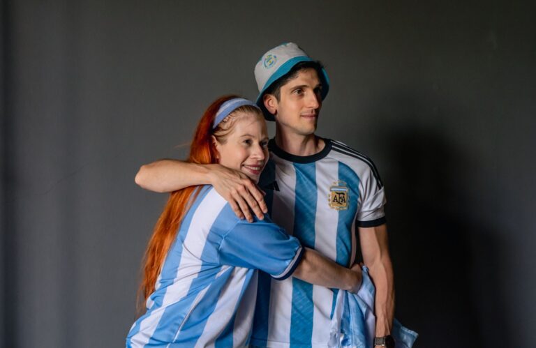A couple in Argentina jerseys embraces, celebrating a soccer game.