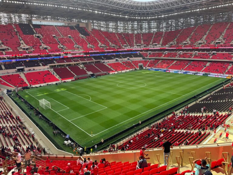 Spacious football stadium with red seating, ready for a match.