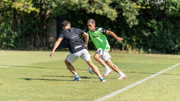 Two soccer players engage in strategic defense practice on a sunny day.
