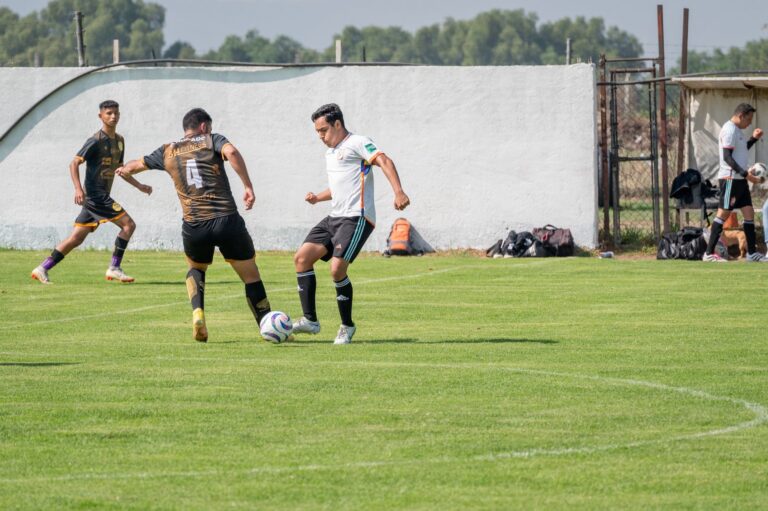 Players engage in a competitive soccer match on an outdoor field during a sunny day.