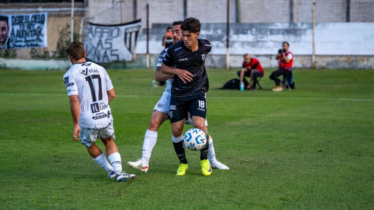 Two soccer players competing intensely on a green field during a daytime match.