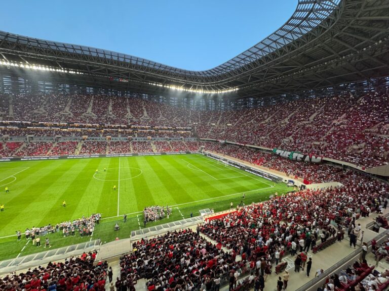 A vibrant football match with cheering fans in a modern stadium.