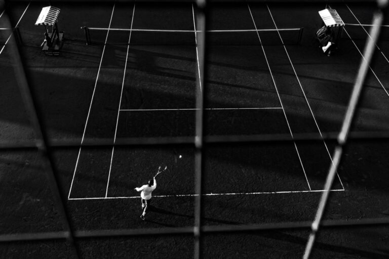 Black and white photo of a tennis match in Buenos Aires, capturing dynamic motion and shadow play.