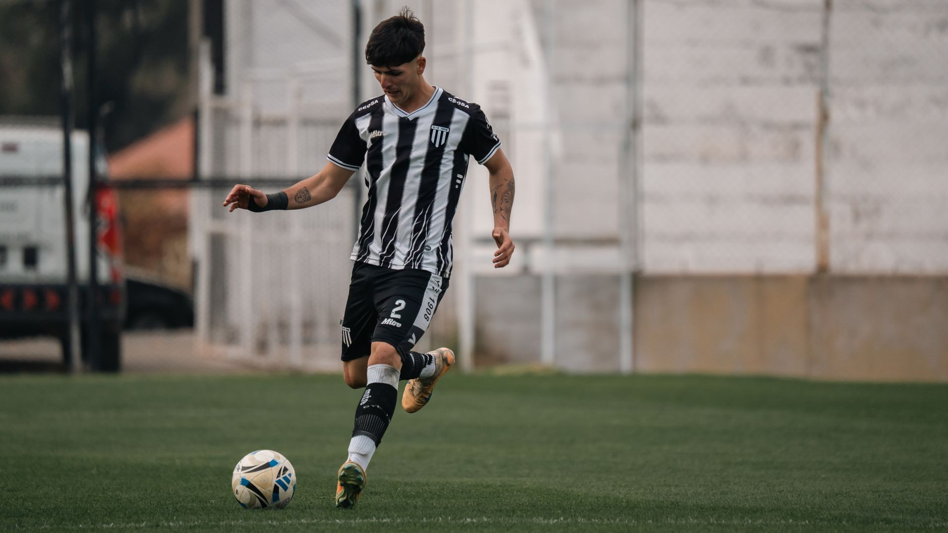 A young soccer player in action, dribbling the ball during a game on the field.