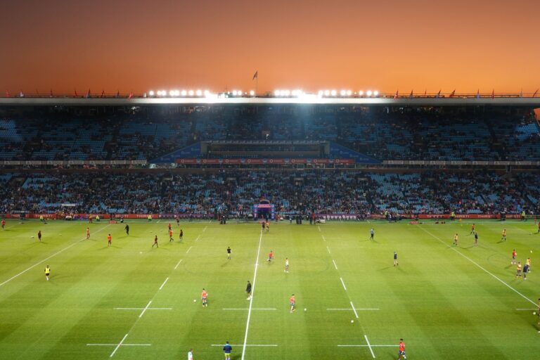 Exciting rugby game unfolding under stunning sunset in large stadium.