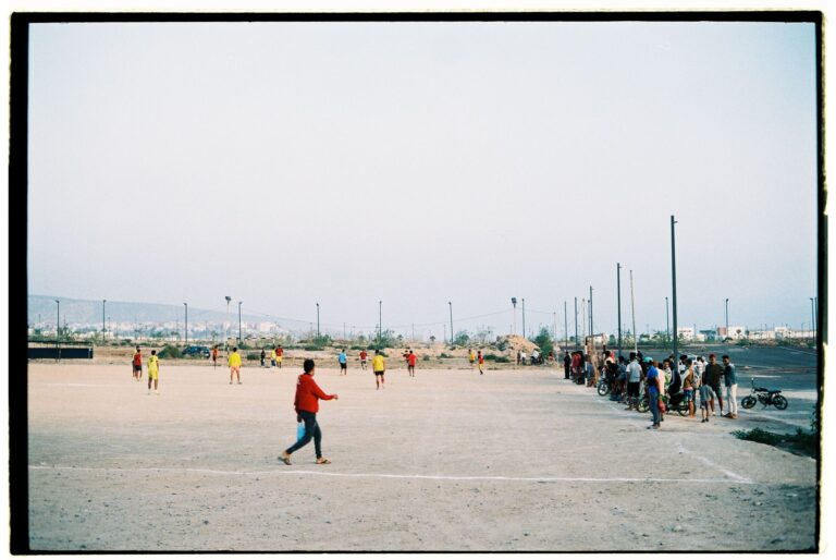 Amateur football match in an open field in Morocco with local players and watchers.