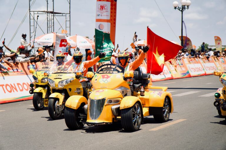 Vibrant motorcycle parade in Hue City featuring riders with flags in a lively street setting.
