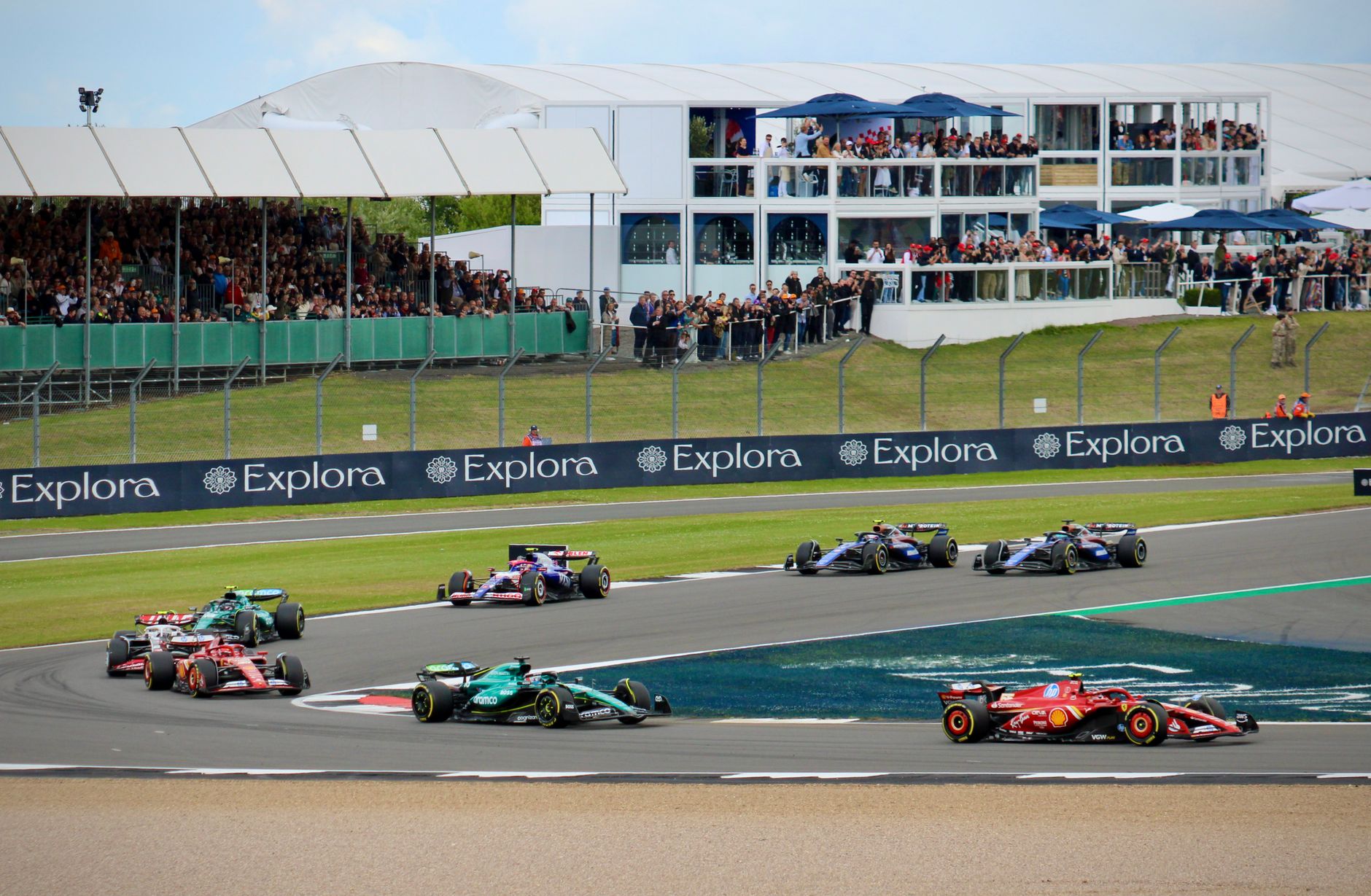High-speed Formula 1 race at Silverstone Circuit, England, with enthusiastic spectators.