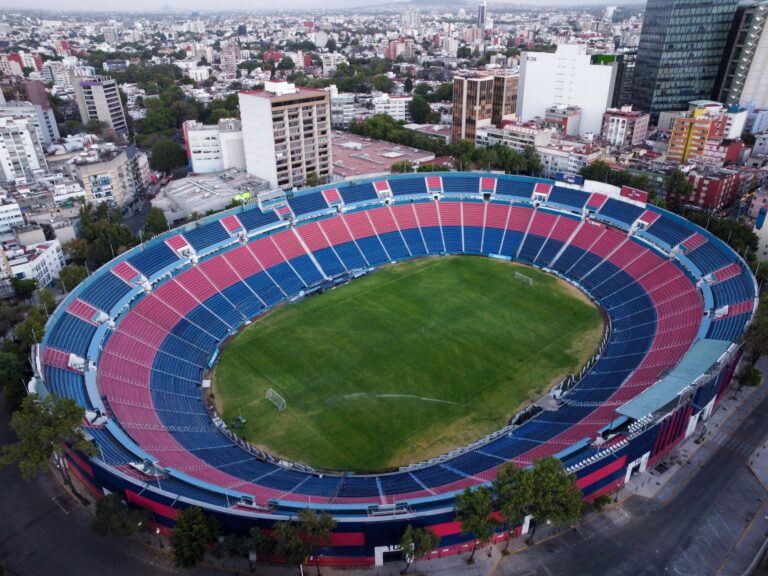 Aerial drone photo of a large empty sports stadium surrounded by city buildings, showing a vibrant urban landscape.