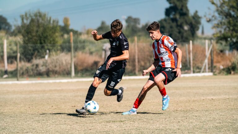 Two young men playing soccer fiercely during a sunny outdoor match.