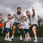Group of enthusiastic soccer fans celebrating victory outside the stadium on game day.