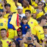 Excited Colombian fans gather with national flags at a football match, showcasing team spirit.