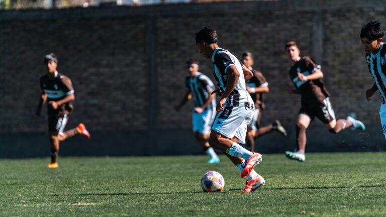 Dynamic soccer match with players running toward the goal on a sunny day.