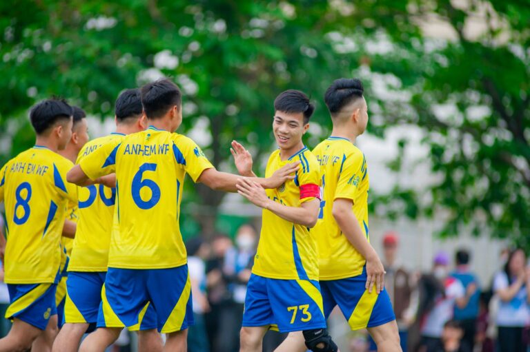Youth soccer team wearing yellow jerseys celebrates during a match in Hanoi, Vietnam.