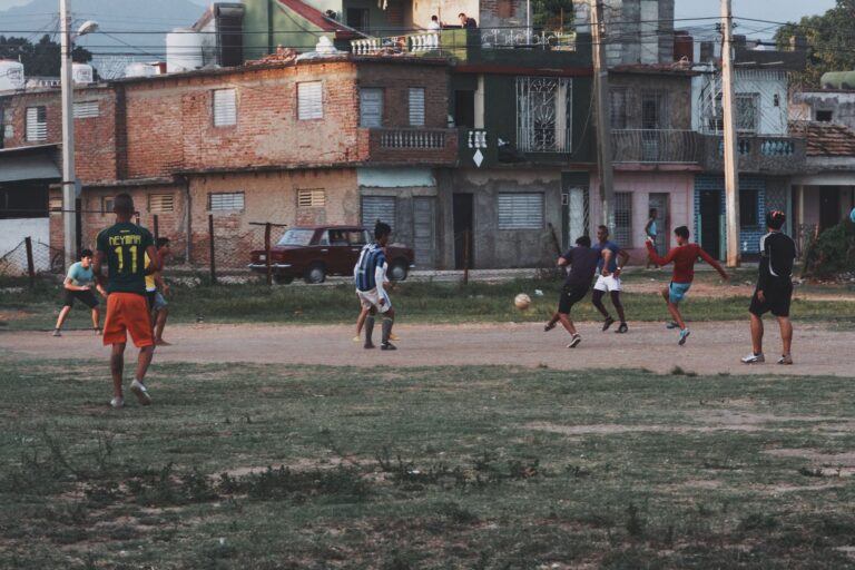 Group of young men playing football on an outdoor field in an urban neighborhood, showcasing community and sports.