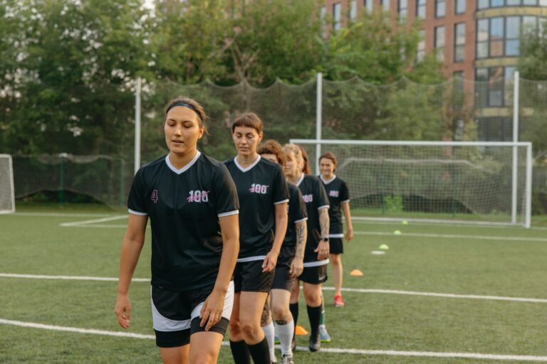 Women soccer players training on a green football field during the day.