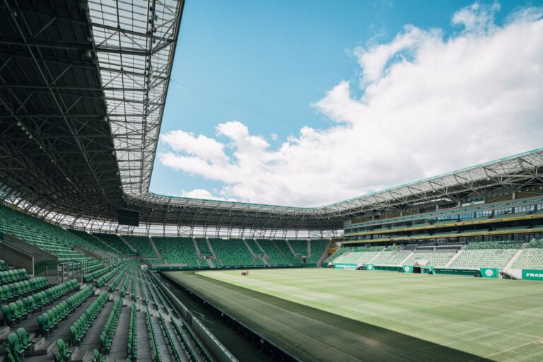 View of a modern stadium in Budapest, Hungary, showcasing green seats and a vast open sky.