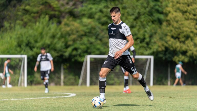 A soccer player is skillfully dribbling the ball on a sunny outdoor field during training.