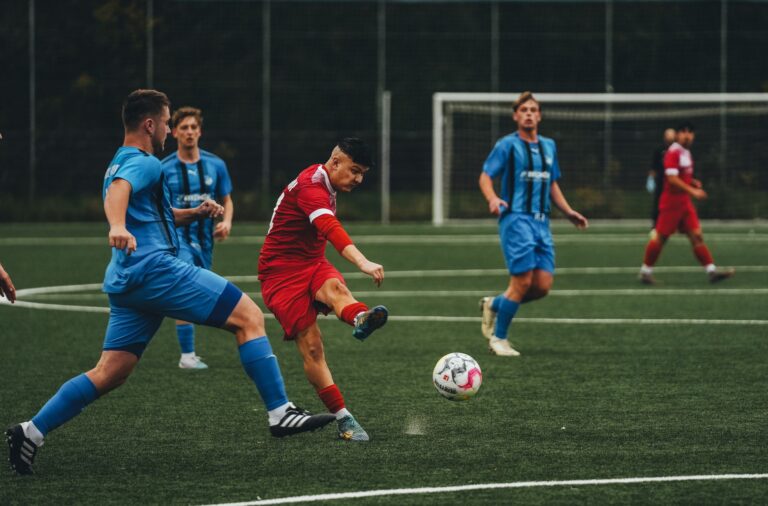 Action-packed soccer match showcasing teams in blue and red uniforms on a grass field.