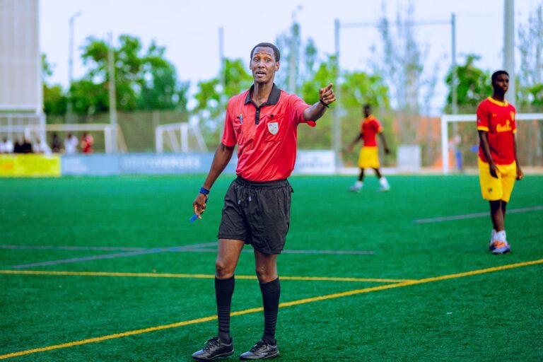 Soccer referee in action on field during a match, guiding players.