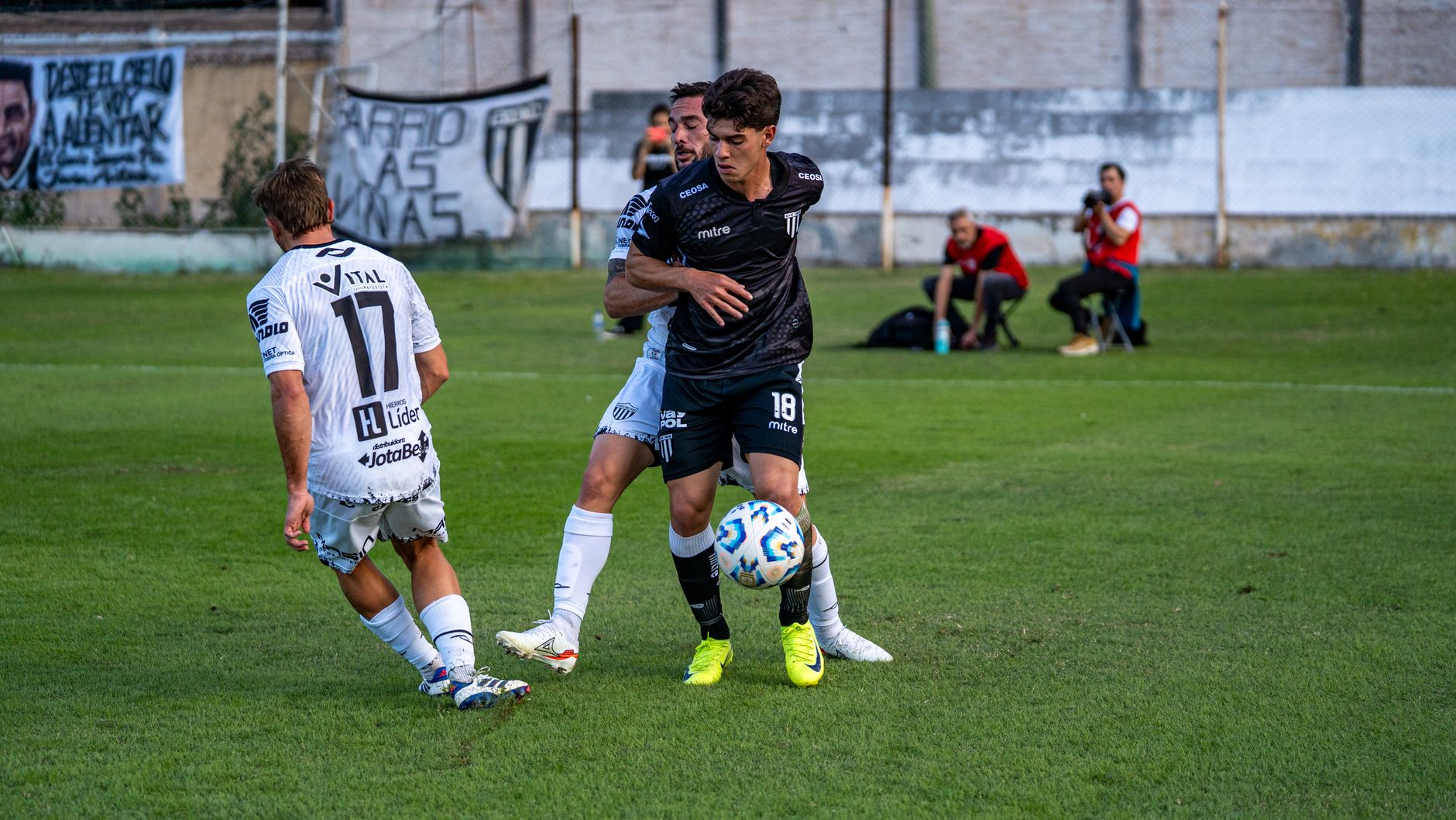 Two soccer players competing intensely on a green field during a daytime match.