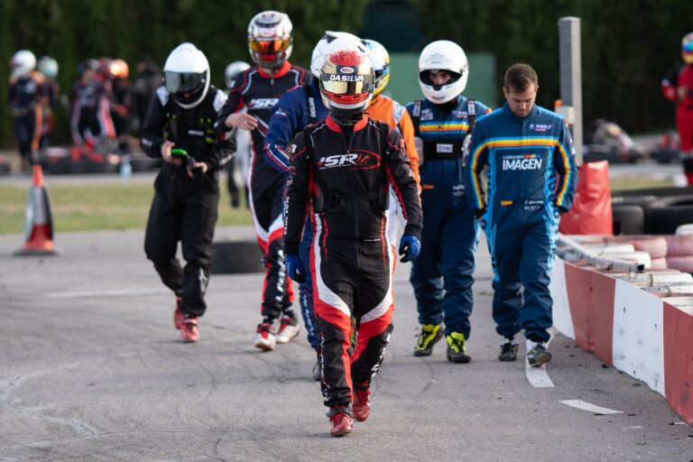 Group of go-kart racers walking on track in racing suits and helmets, signaling an exciting motorsport event.
