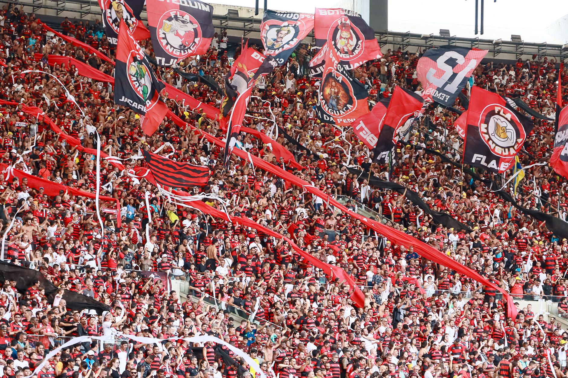 Energetic crowd of Flamengo supporters waving flags in Maracanã Stadium, Rio de Janeiro.