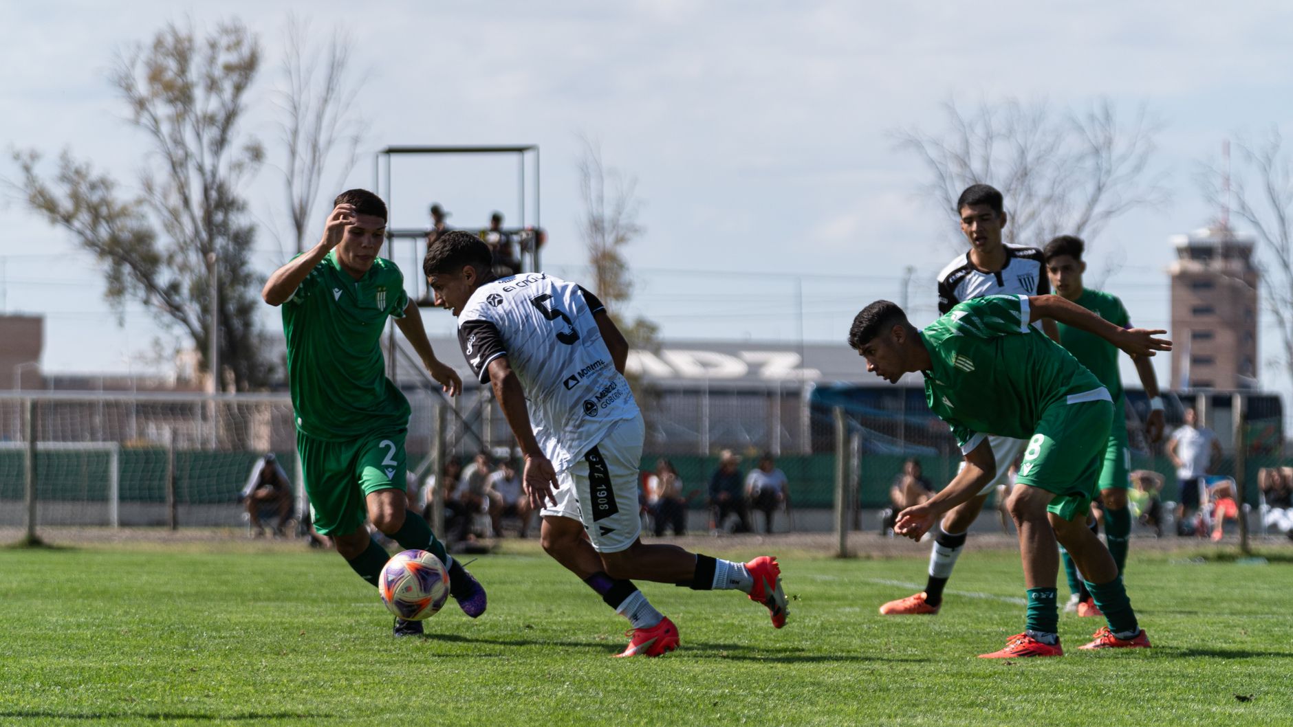 Soccer players in action during a competitive match on a sunny day.