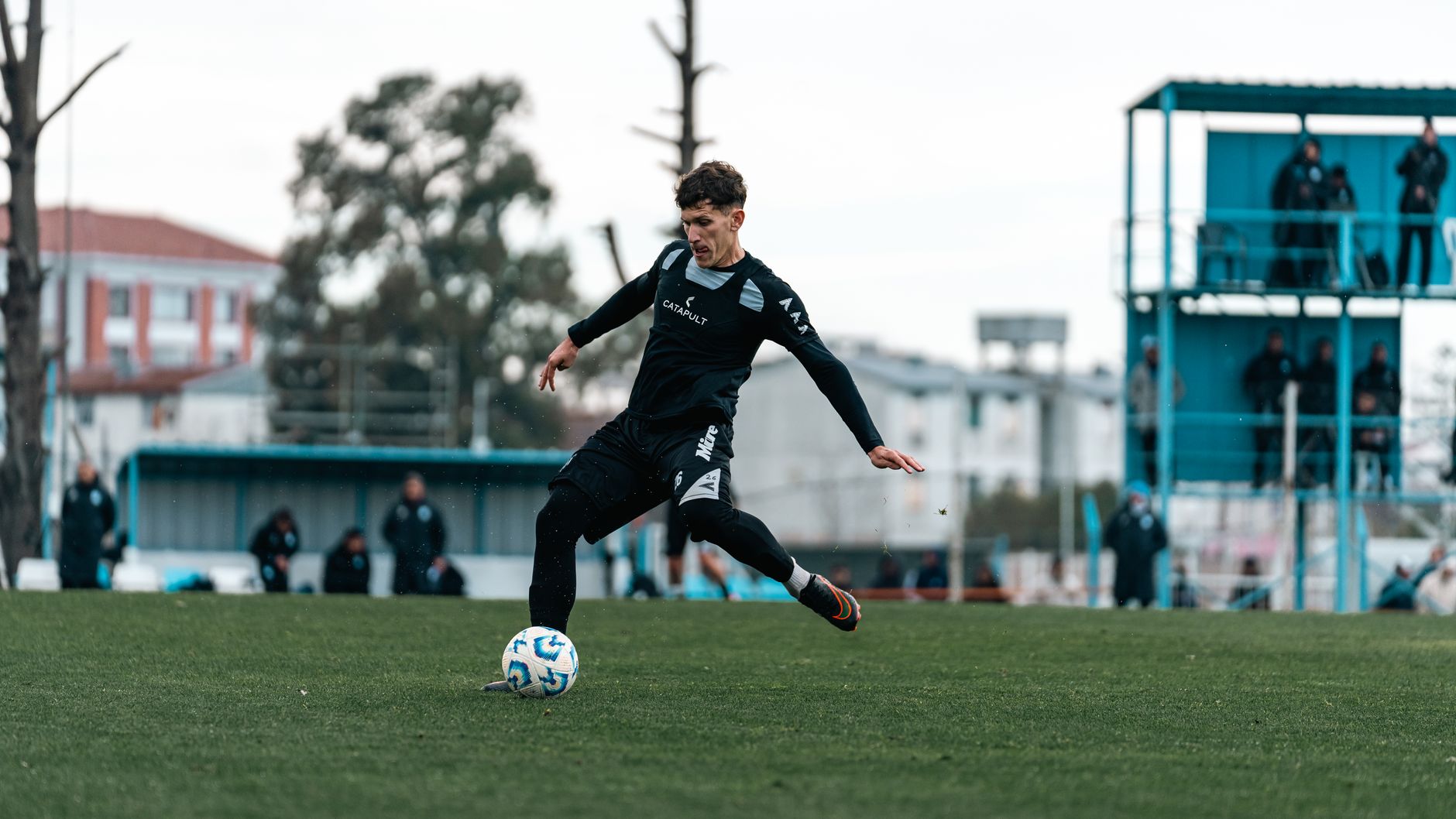 Football player in action during outdoor match in modern sportswear.
