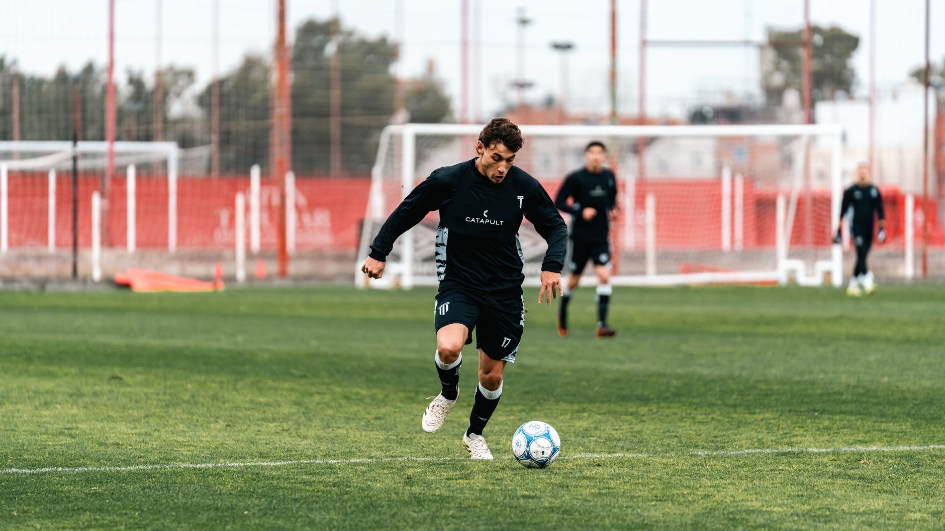 Young soccer player dribbling ball on a grassy field during practice.