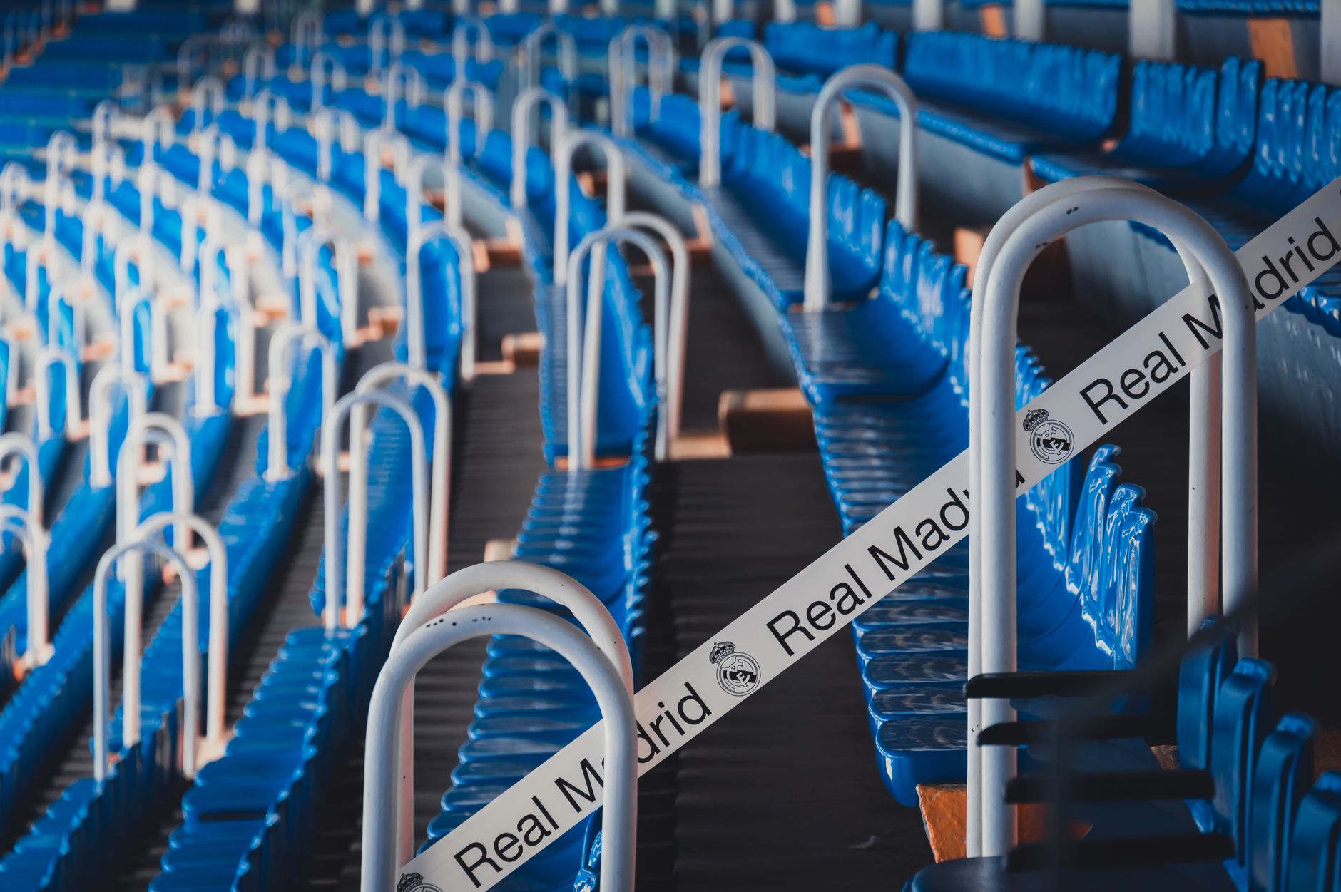 Rows of blue stadium seats in Madrid's iconic Bernabéu Stadium, featuring Real Madrid branding.