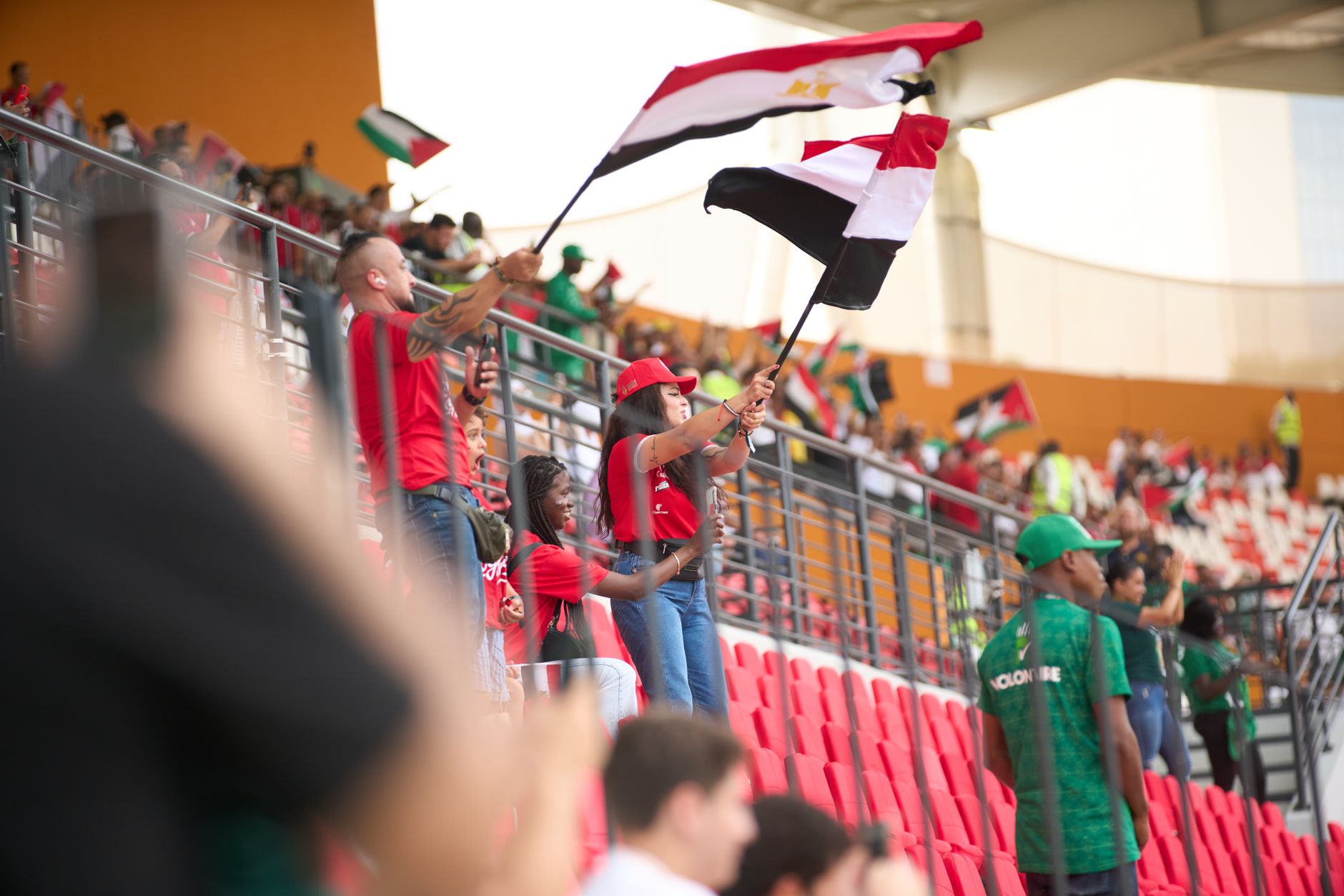 Soccer fans in the stadium wave Egyptian flags, showing their support during a lively sports match.