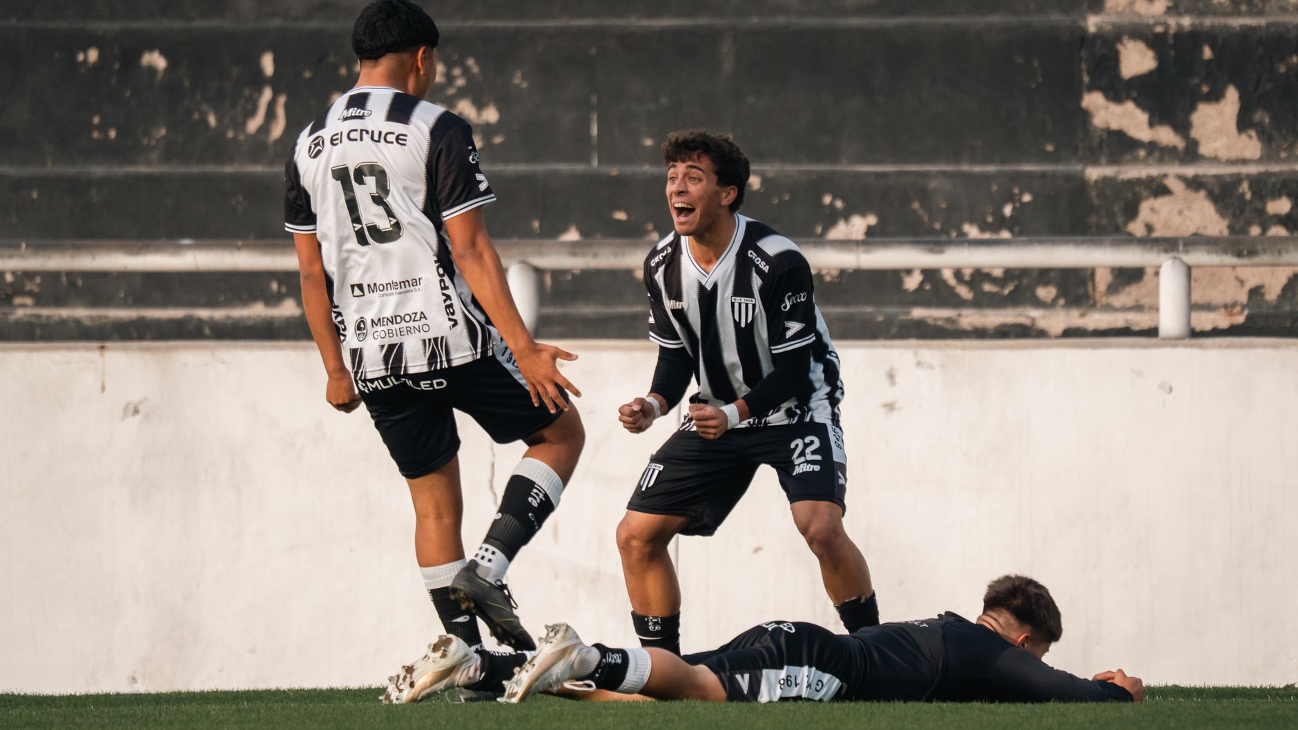 Football players in black and white jerseys celebrate a goal on the field.
