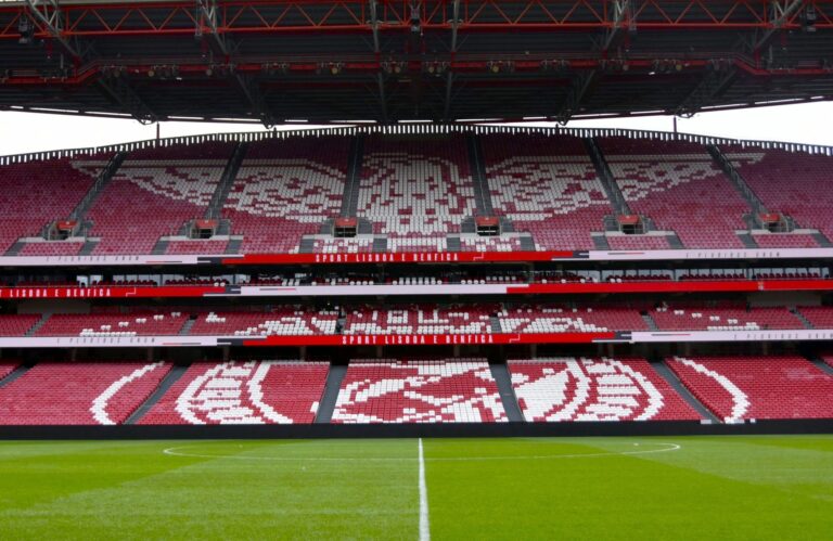 Wide-angle view of the iconic Estádio da Luz stadium in Lisbon, Portugal, showcasing its red seating and field.